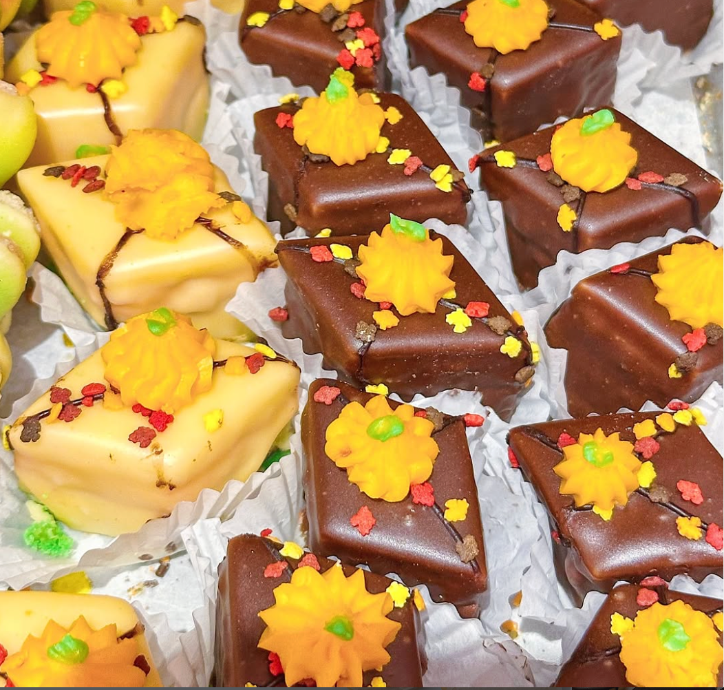 Assorted petit fours with pumpkins and Thanksgiving designs from William Greenberg Desserts on a white paper background