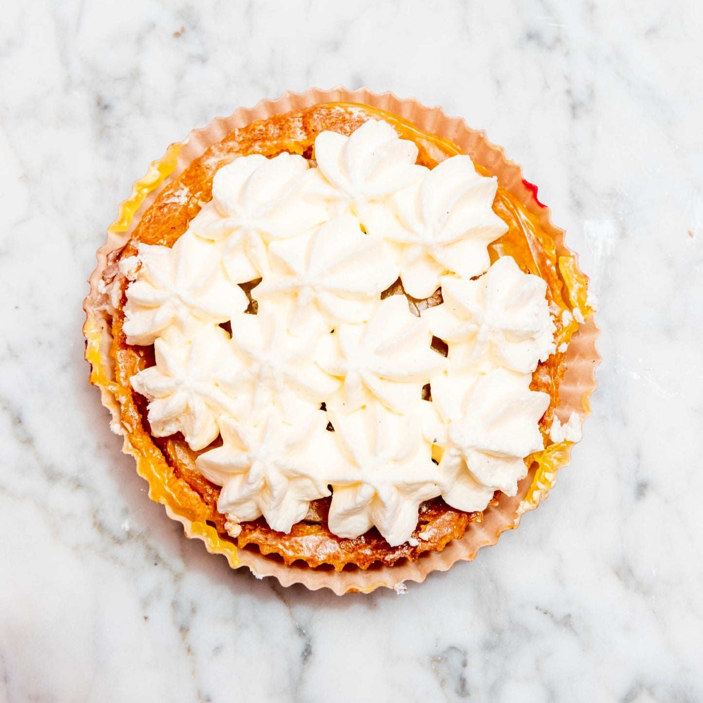 individual lemon meriangue tart with white cream on a marble surface