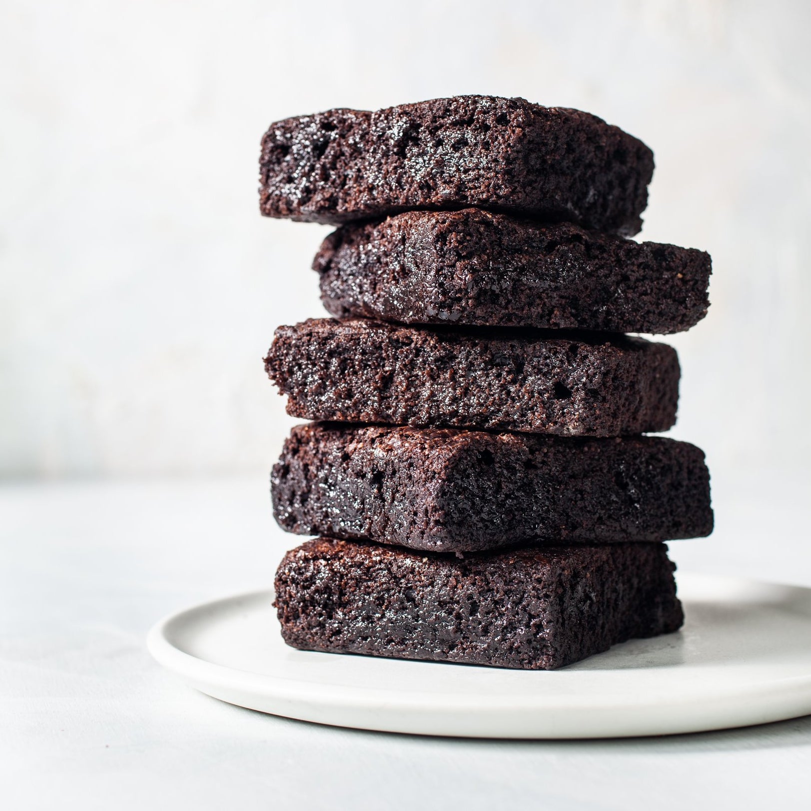 Stack of 5 brownies on a white plate.