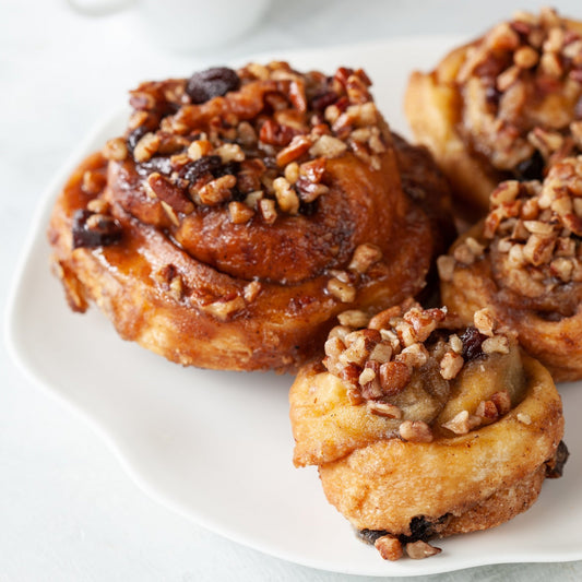 Lare and mini schnecken studded with pecans on a white plate.