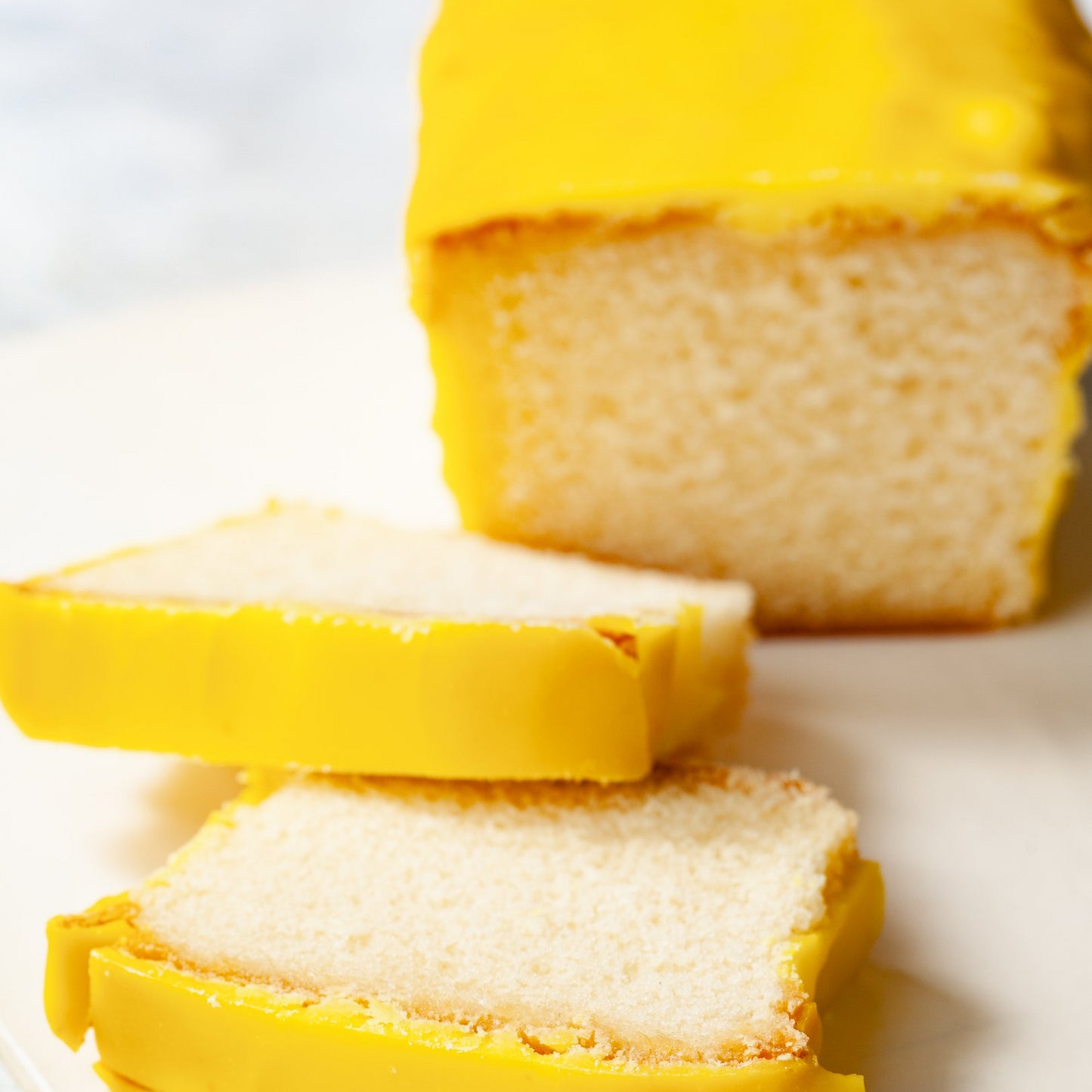 Two sliced and a half lemon pound cake on a white plate