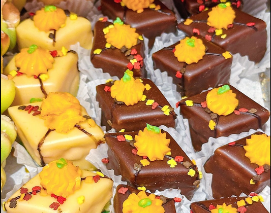 A tray of beautifully decorated bite sized William Greenberg Desserts Thanksgiving themed petit fours in orange and brown.