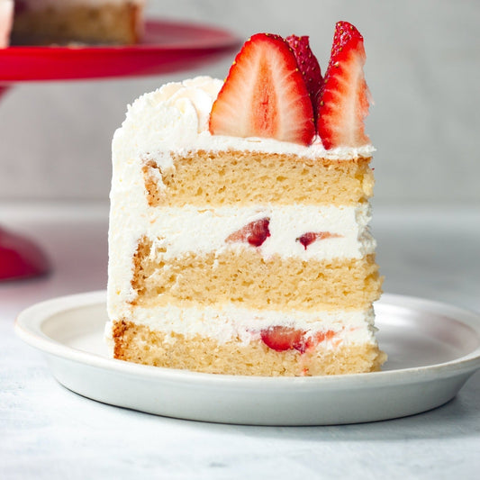A picture of a piece of strawberry cream cake with a fine, delicate crumbyet sturdy enough to perfectly showcase fresh cream and vibrant red berries.