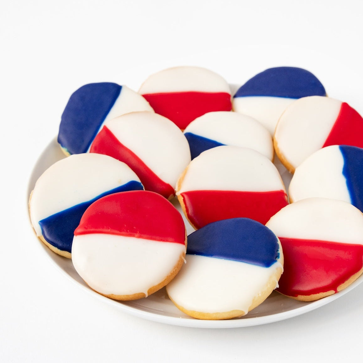 Plate of William Greenberg Desserts Black & White cookies with red, white, and blue icing on a white plate