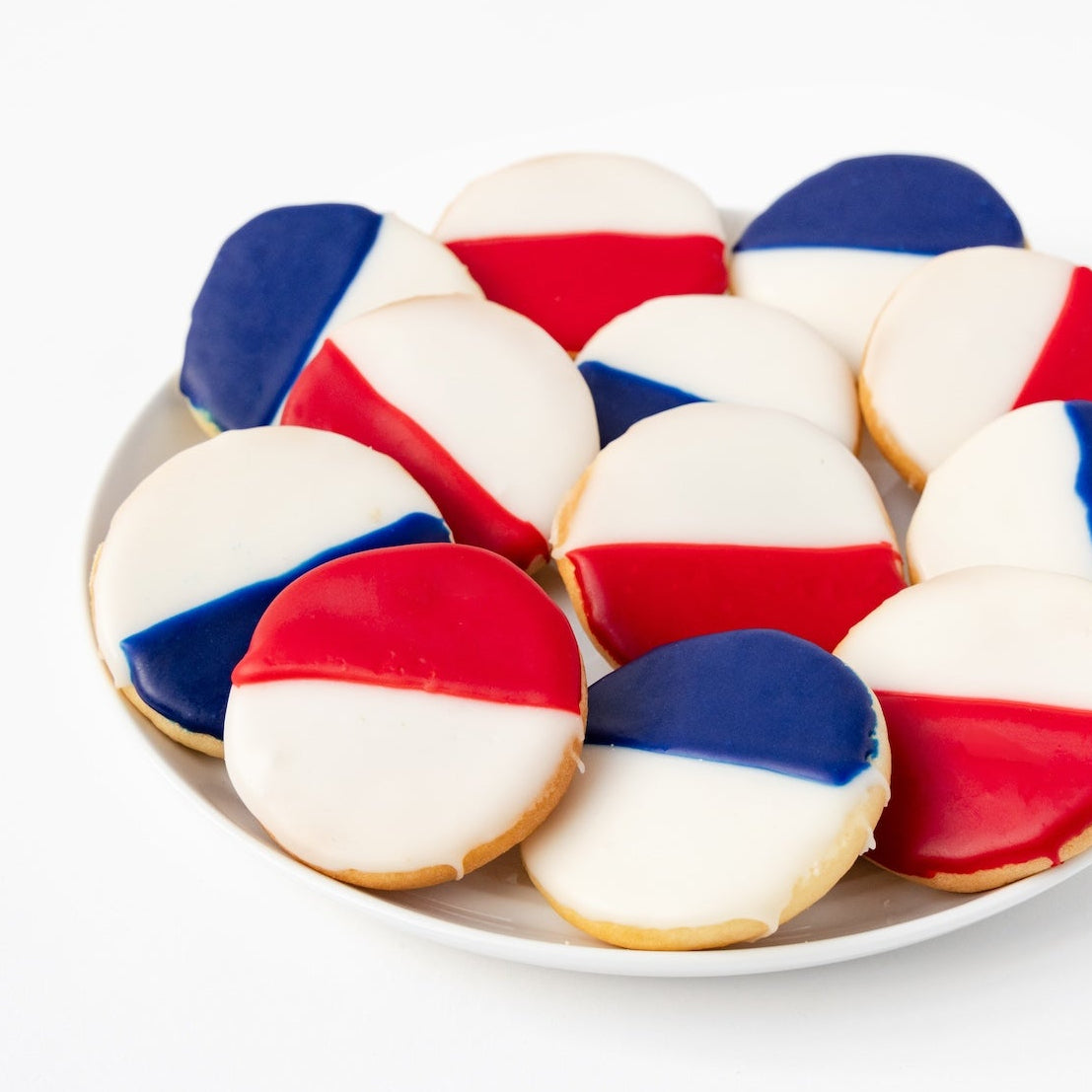 Plate of William Greenberg Desserts Black & White cookies with red, white, and blue icing on a white plate