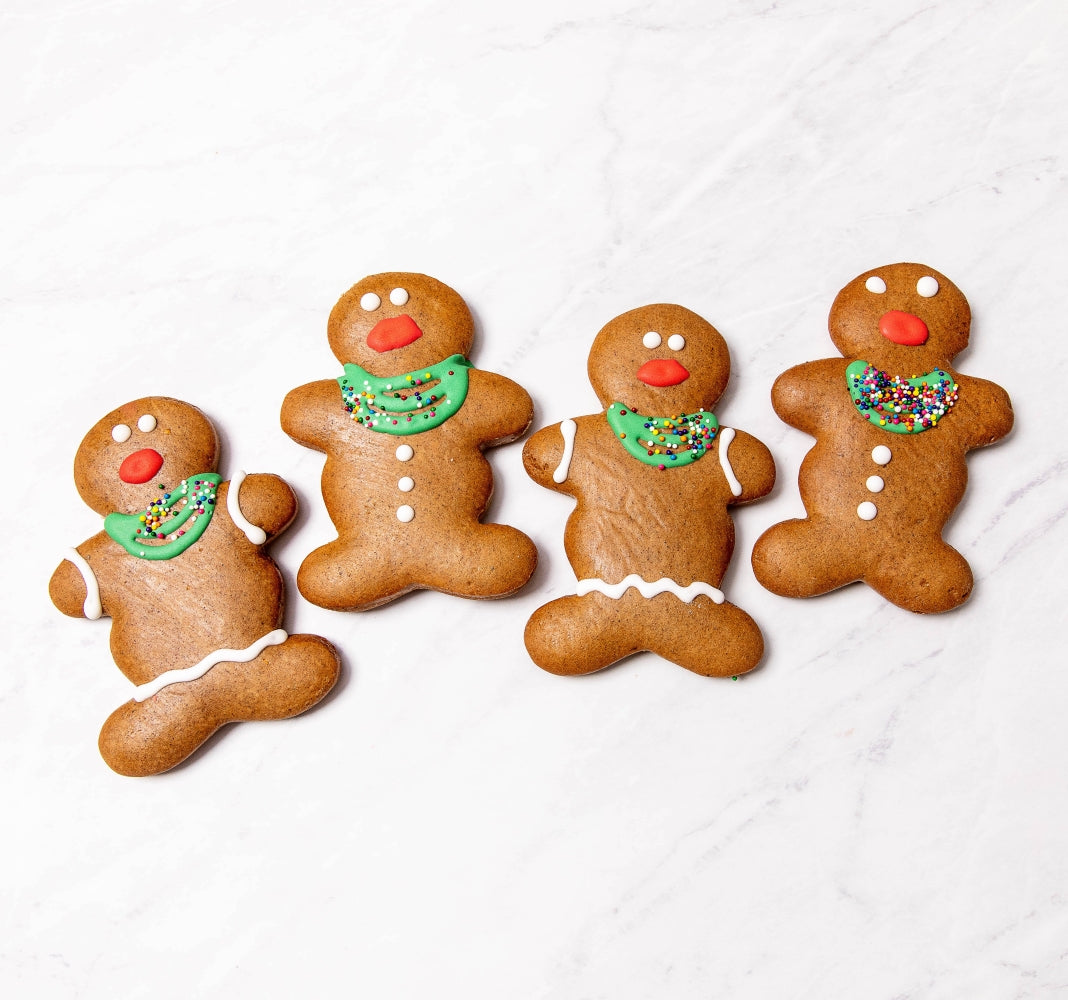 Four gingerbread people on a white marble background.