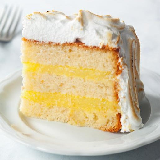 Slice of lemon meringue cake on a white plate