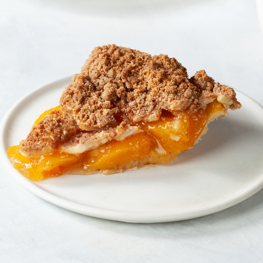 A slice of peach pie on a white plate from William Greenberg Desserts