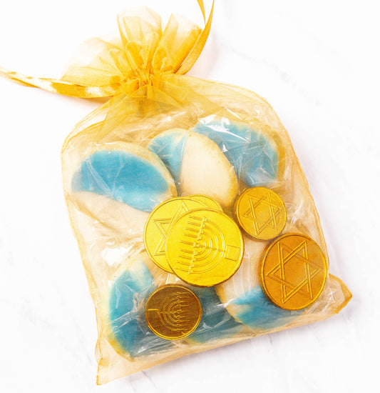 Gelt bag containing chocolate coins, blue & white cookies and dreidel.